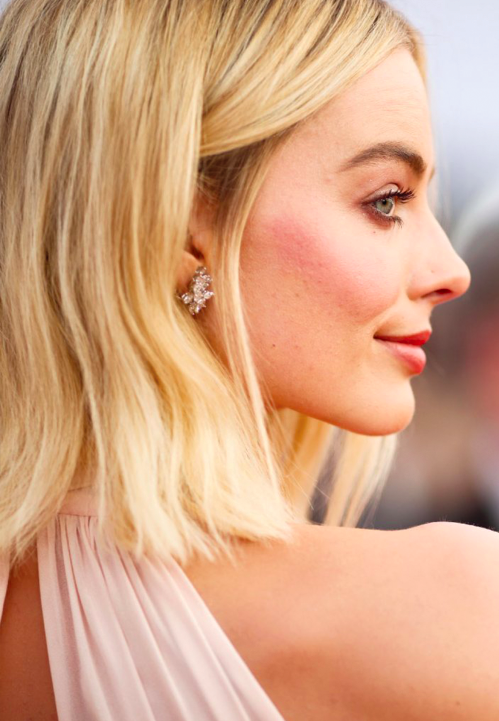 Margot Robbie in a baby pink Miu Miu dress with diamond and platinum earrings.